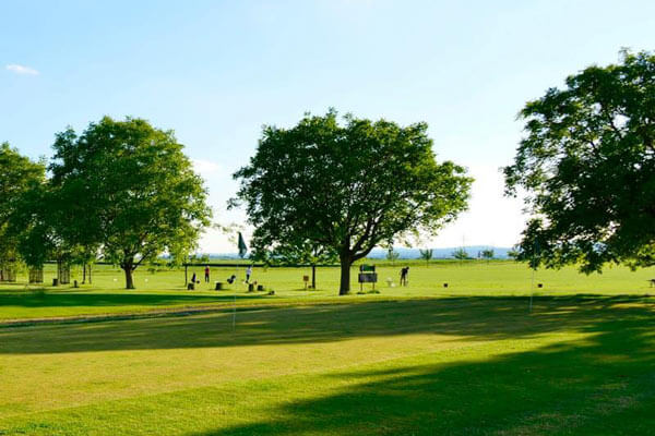 Weitläufige Golf Driving Range in Karben mit Spielern und Golfbällen auf dem Rasen.